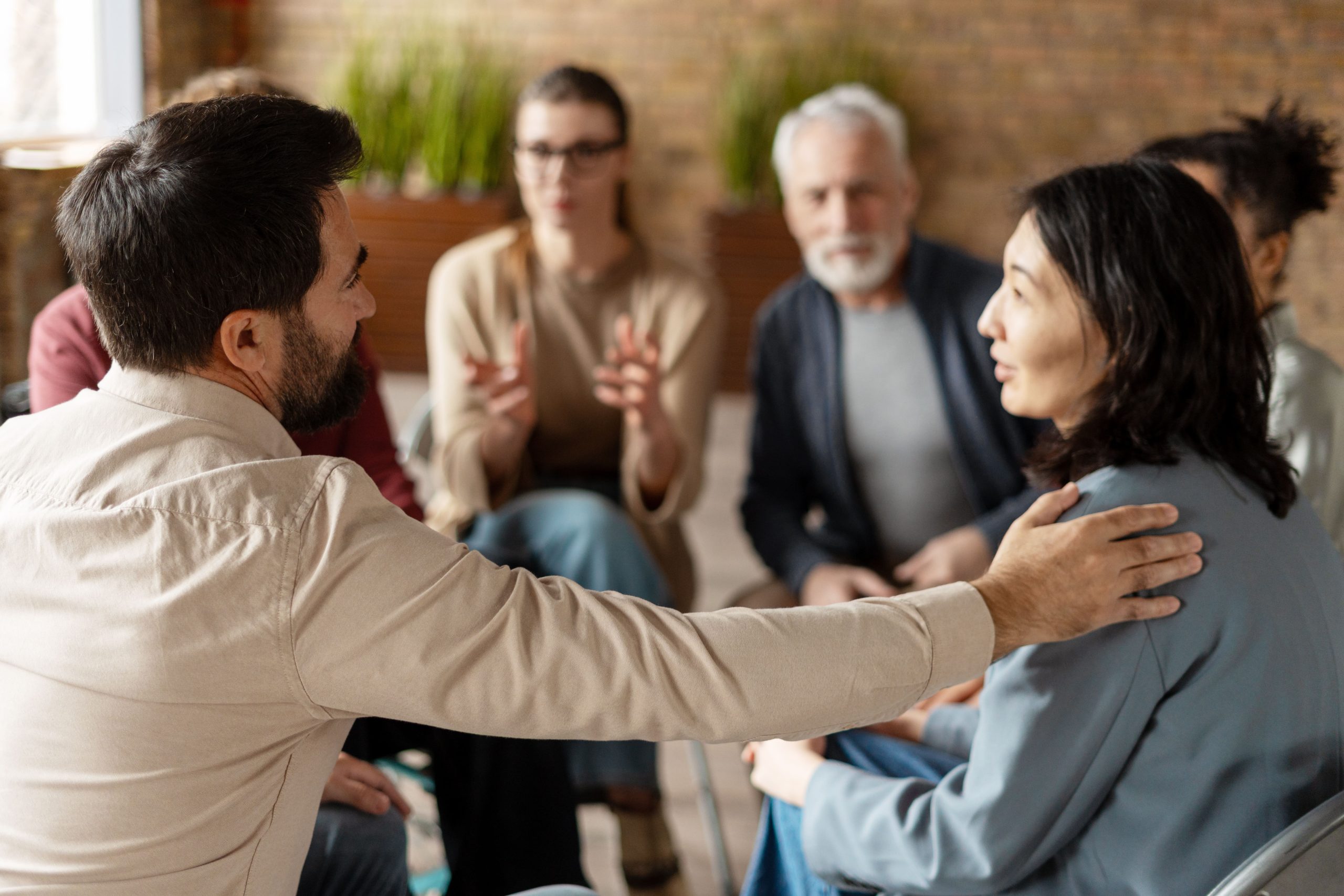 Grupo de personas conversando y apoyándose durante una reunión en una oficina luminosa