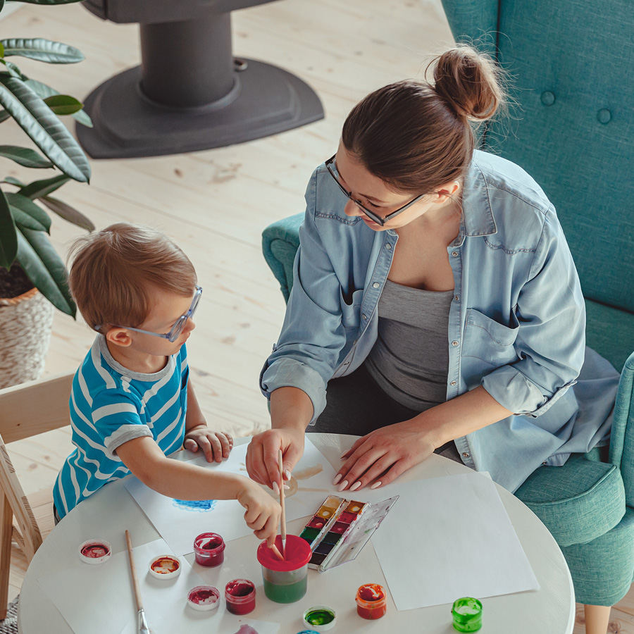 Profesional y un niño pintando juntos en una mesa durante una actividad